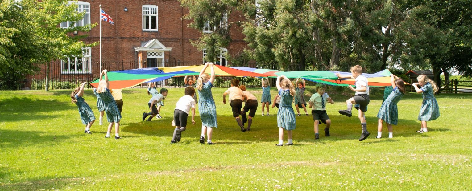 school children playing with a parachute