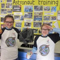 children standing in front of astronaut training board