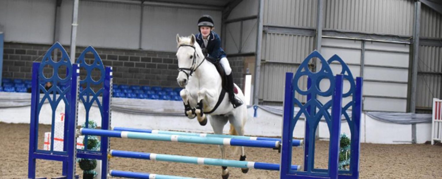 A student jumping over a stand with a horse