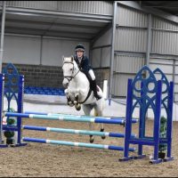 A student jumping over a stand with a horse