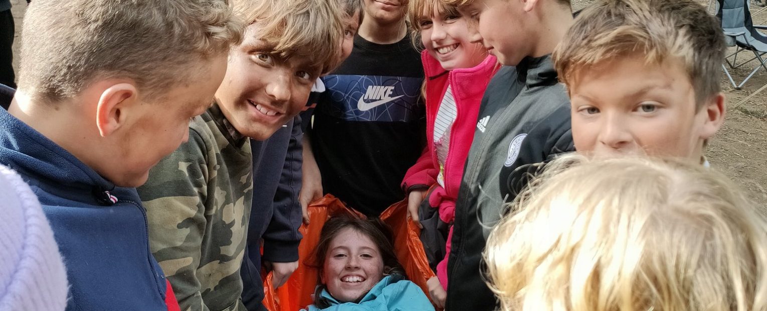 students crowded around a girl in an orange bag being carried